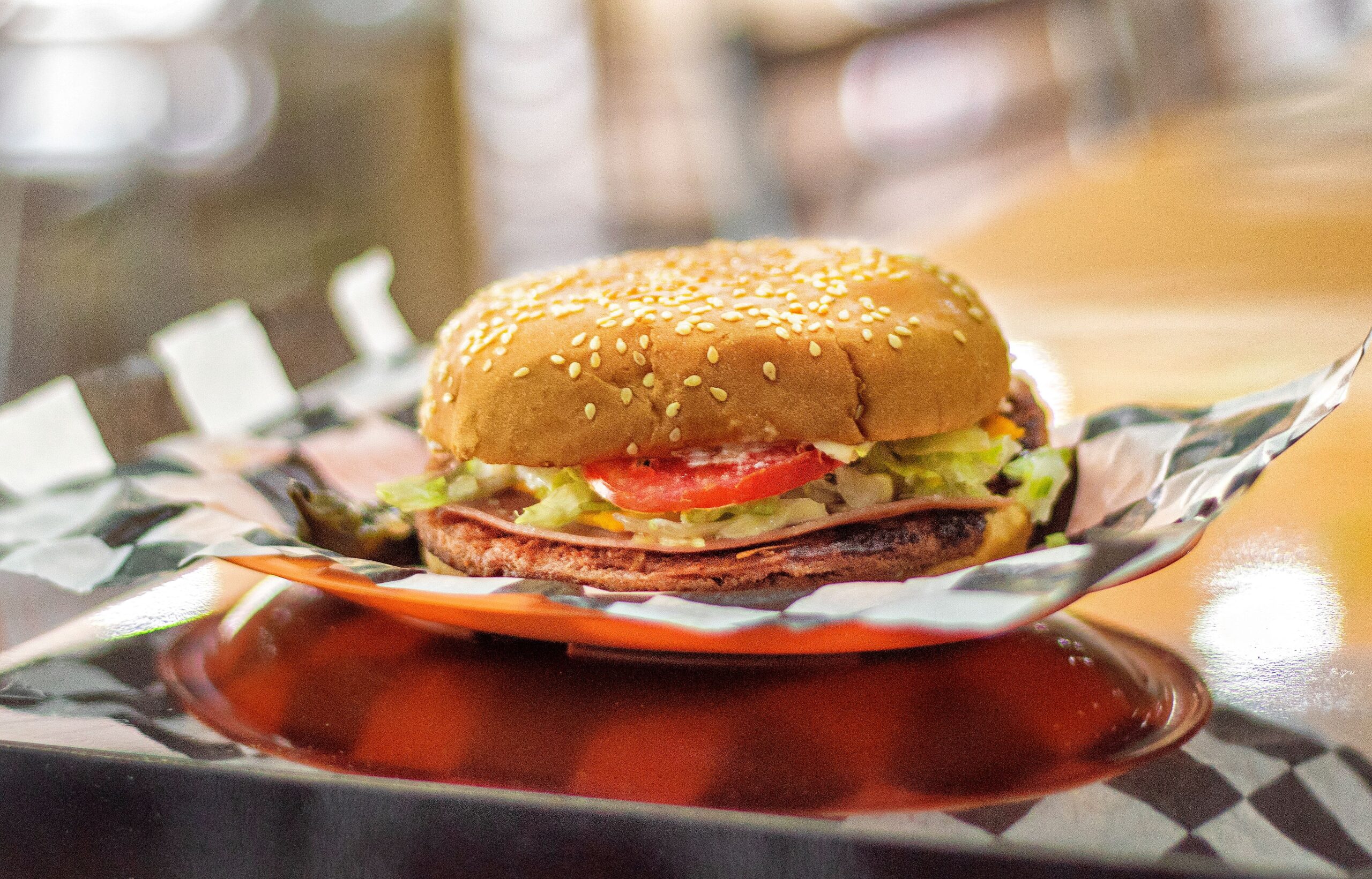 Tasty beef hamburger with lettuce, tomato, and cheese on sesame bun.